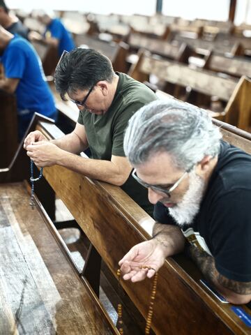 Homens em oração nos bancos da igreja