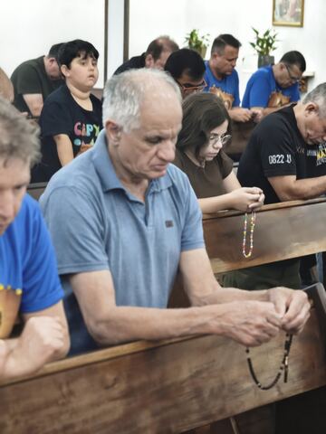 Homens sentados nos bancos durante o terço