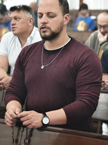 Homem em oração com o terço nas mãos