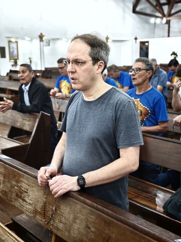Homem acompanhando a oração nos bancos