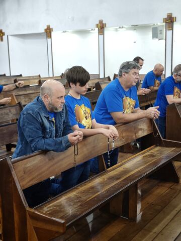 Homens rezando o terço nos bancos da igreja