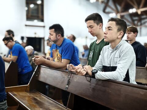 Menino e homens com o terço nos bancos