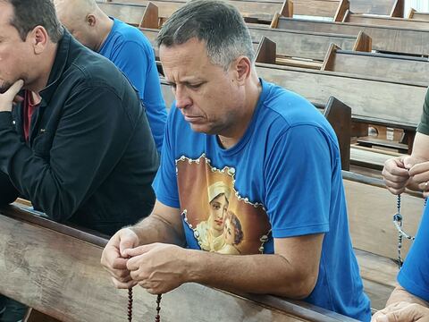 Homem com a camiseta do grupo e o terço