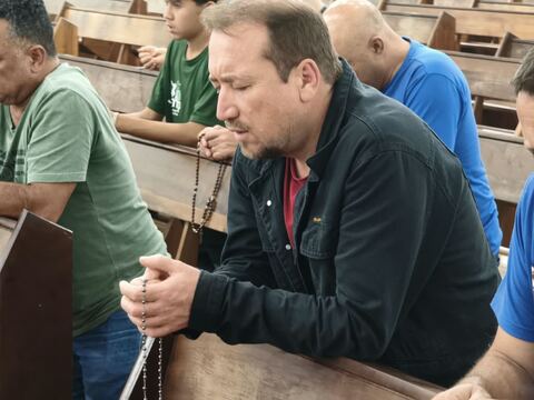 Homem em oração nos bancos da igreja