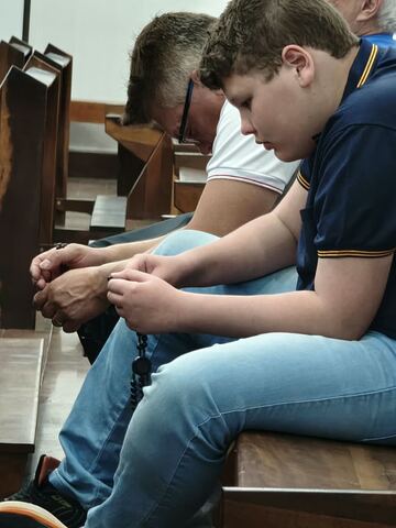 Menino e adulto com o terço nos bancos