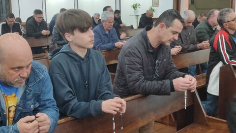 Homens rezando o terço nos bancos da igreja