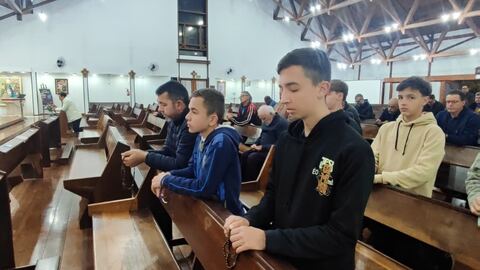 Jovens e adultos em oração com o terço nas mãos