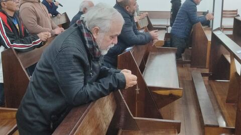 Mãos com o terço apoiadas no banco