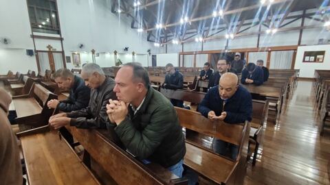 Homem em oração com o terço nas mãos
