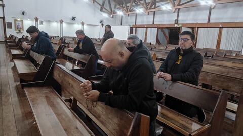 Homens rezando o terço nos bancos da igreja