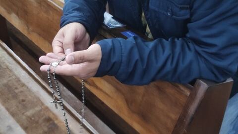 Terço azul nas mãos de um participante