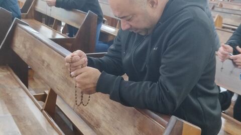 Mãos com terço de madeira em oração